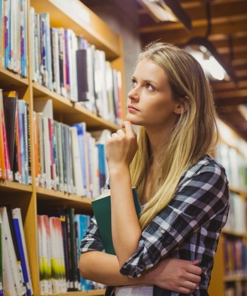 Studentin schaut auf Bücherregal